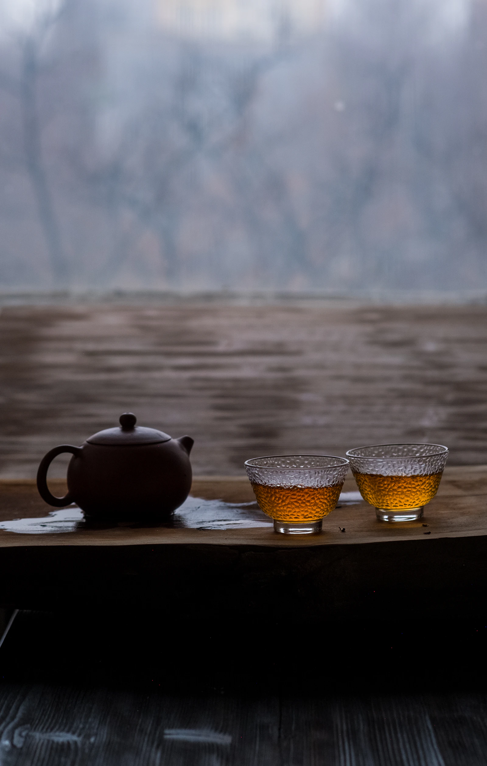 A small clay teapot beside two glass cups of amber tea
