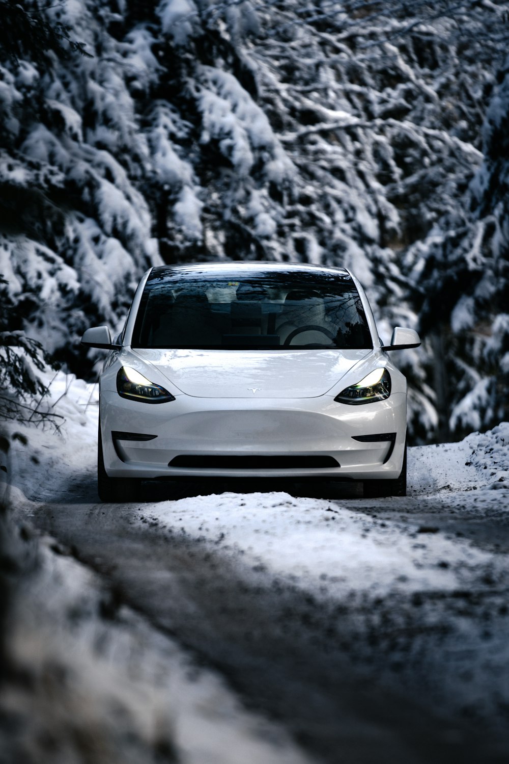 a white car driving down a snow covered road