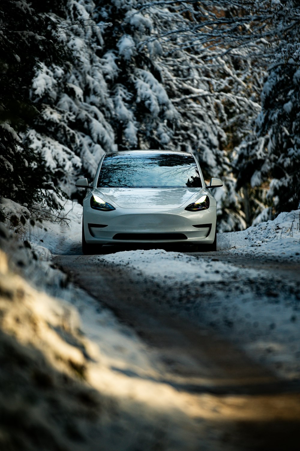 Ein weißes Auto fährt eine schneebedeckte Straße hinunter