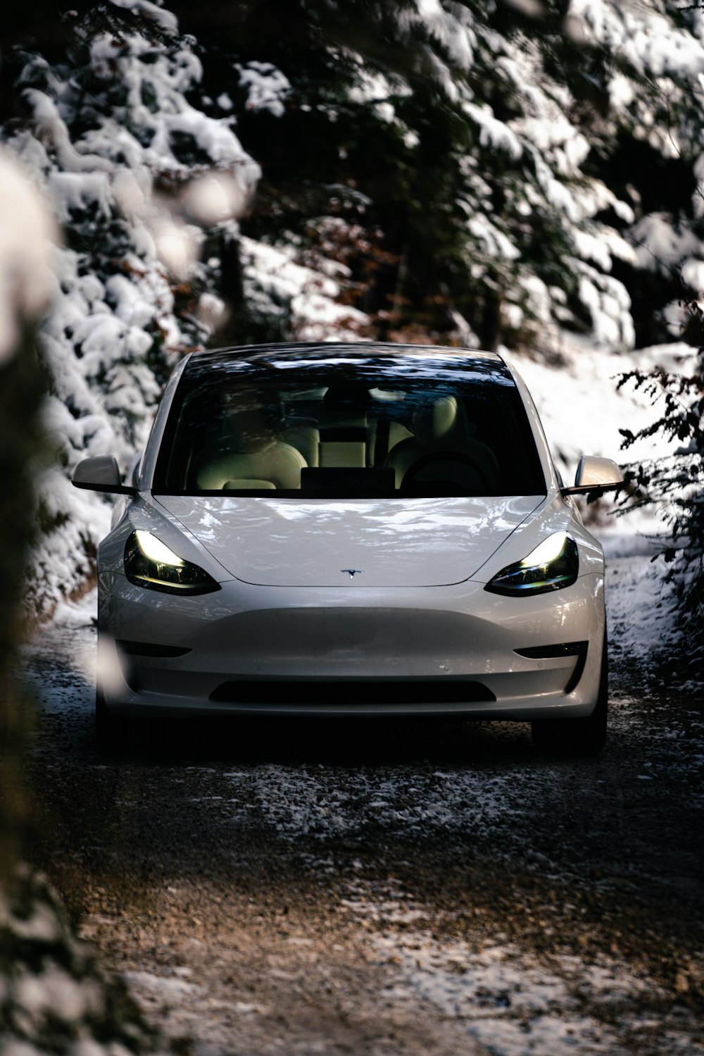 a white car driving down a snow covered road