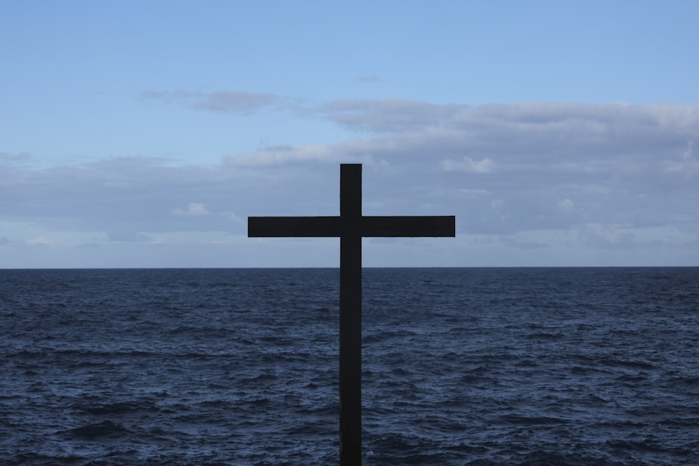 a cross on a pole in the middle of the ocean