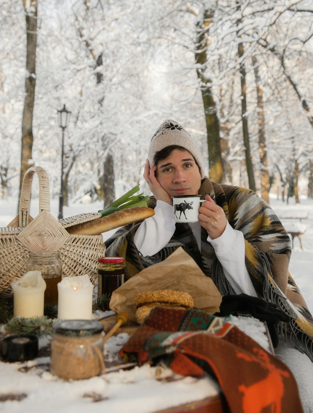 um homem sentado na neve segurando uma xícara de café