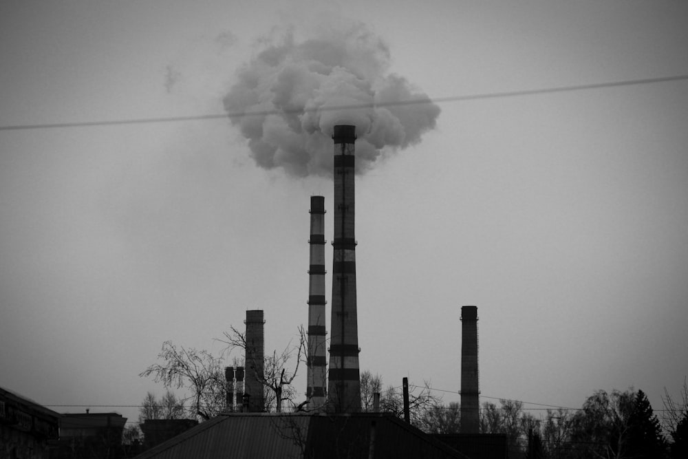 a smokestack emits from a factory in a black and white photo