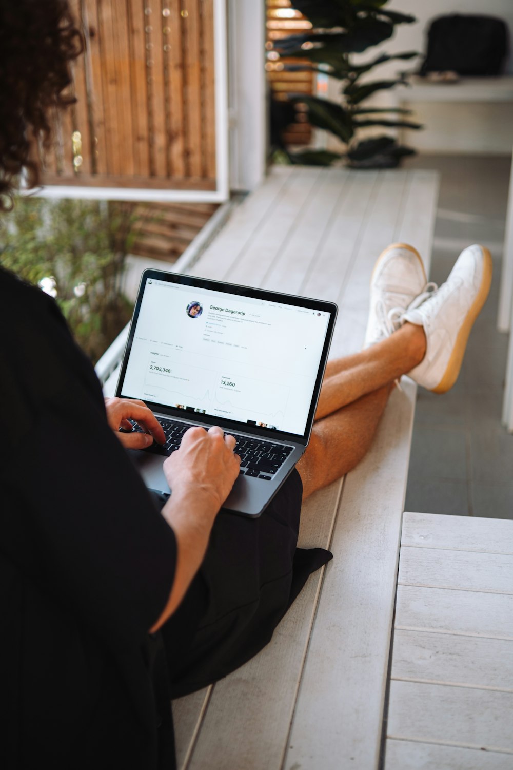 a person sitting on a porch using a laptop