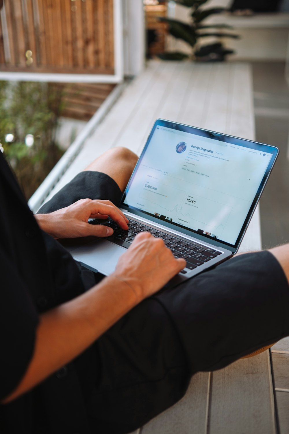 a person sitting on a porch using a laptop