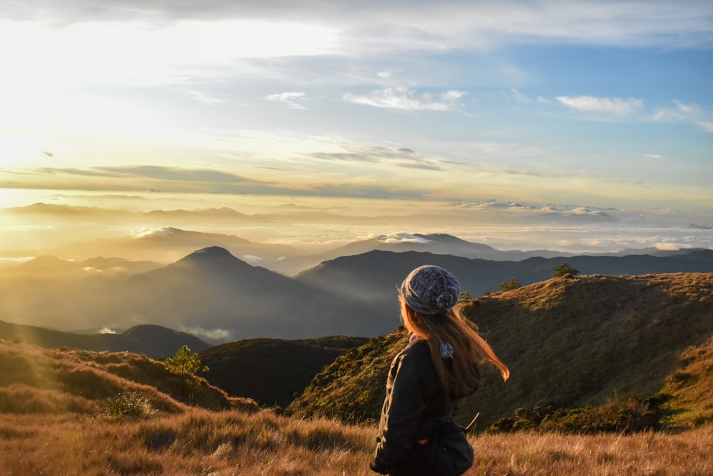 Una donna in piedi sulla cima di una collina coperta di erba