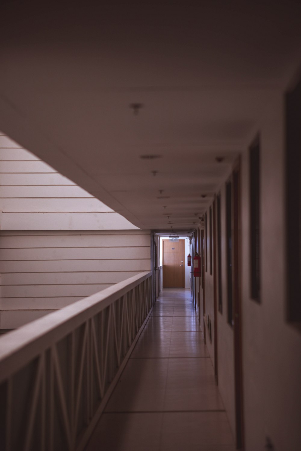 a long hallway with white walls and a red door