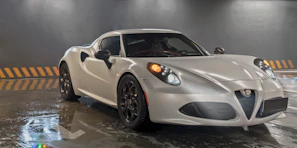 A high-performance car parked under metallic silver lighting, highlighting its curves.