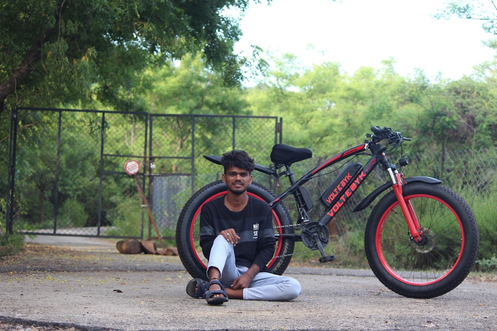 a man sitting on the ground next to a bike