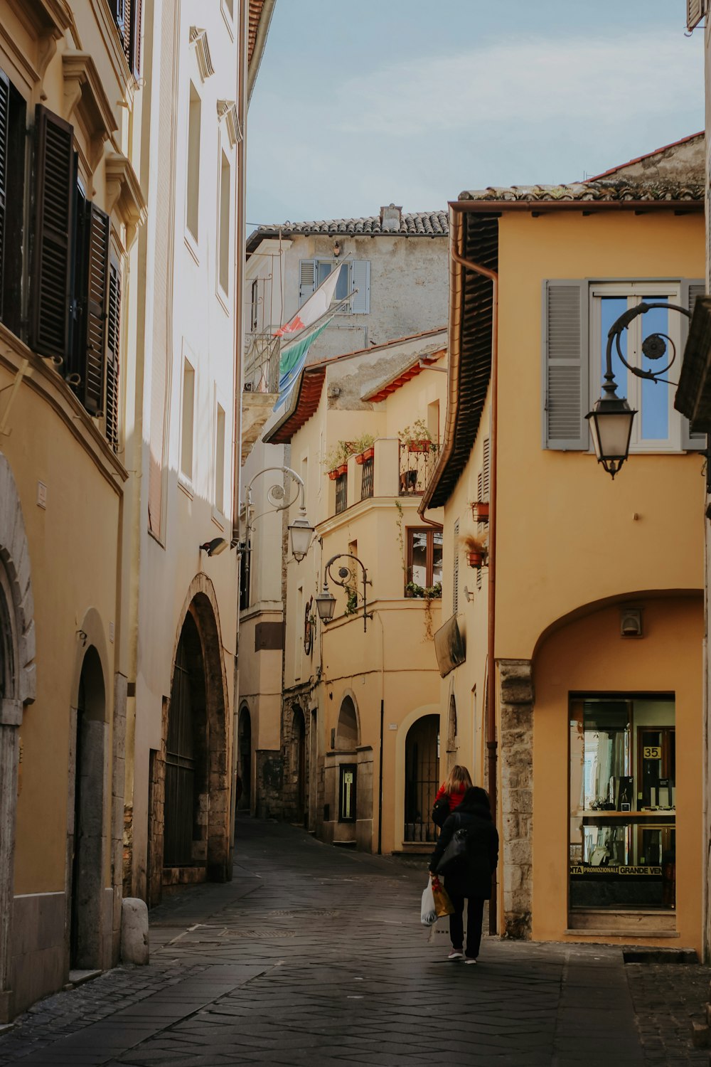 a couple of people walking down a street next to tall buildings