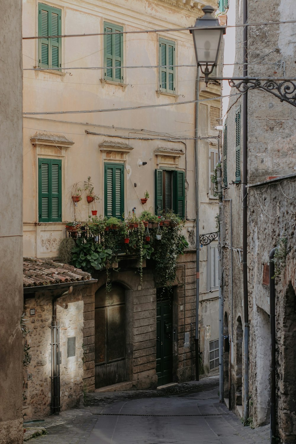 a narrow alley way with green shuttered windows