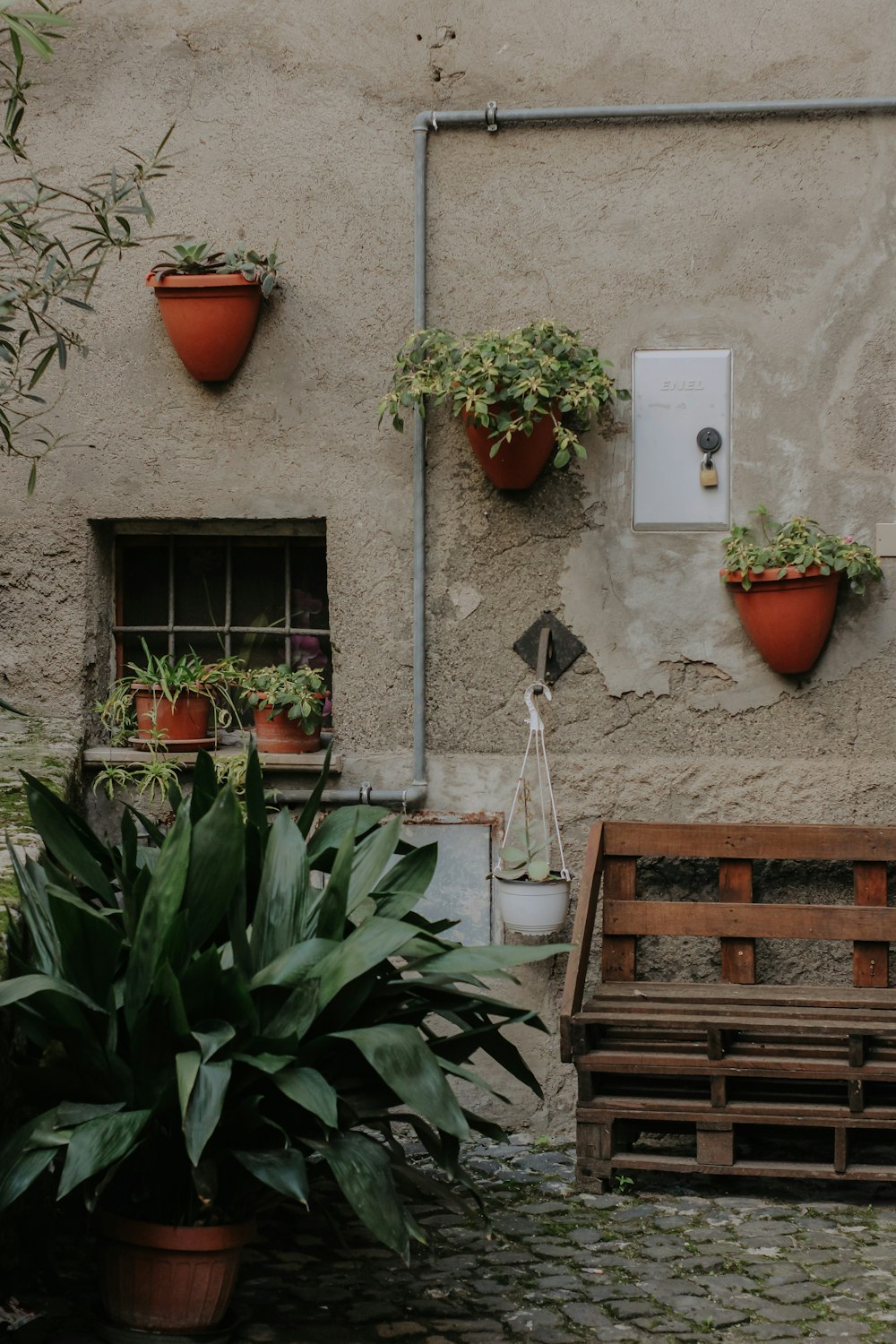 a building with potted plants and a bench in front of it