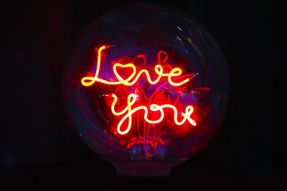 a neon sign that says love you inside of a glass ball
