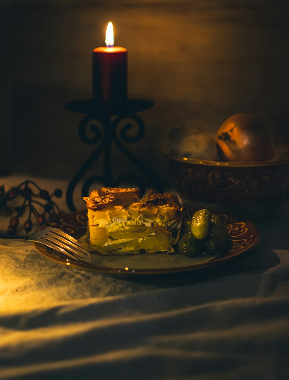 a plate with a piece of pie on it next to a lit candle