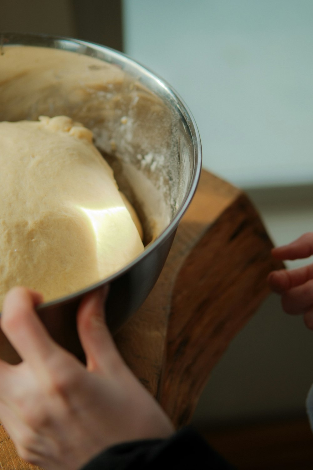 a person holding a metal pan with dough in it