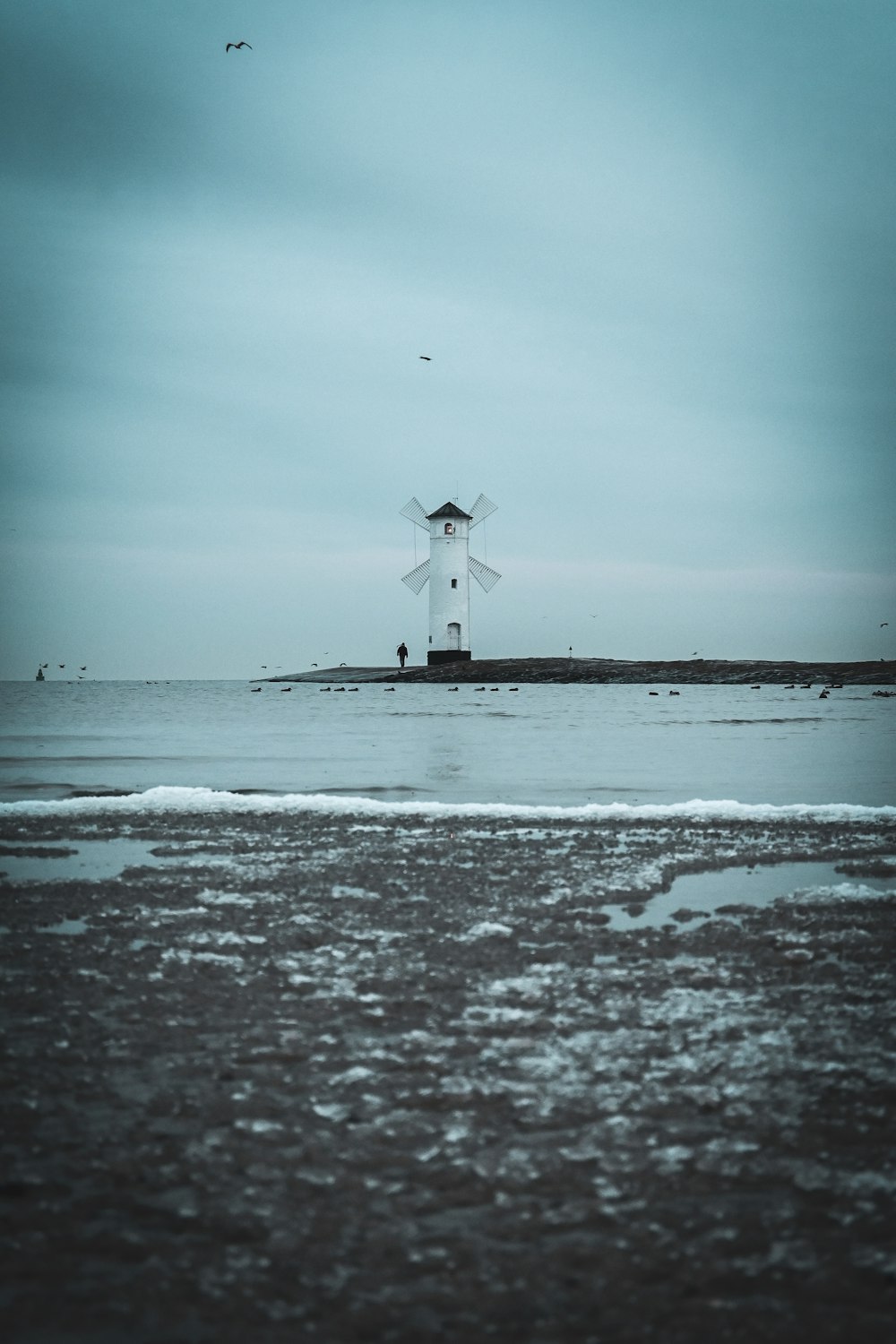 a large white windmill sitting on top of a beach