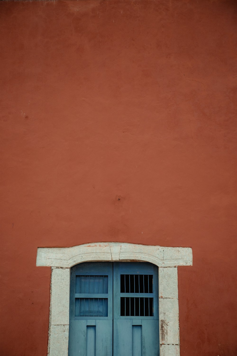 una pared roja con una puerta y ventana azules