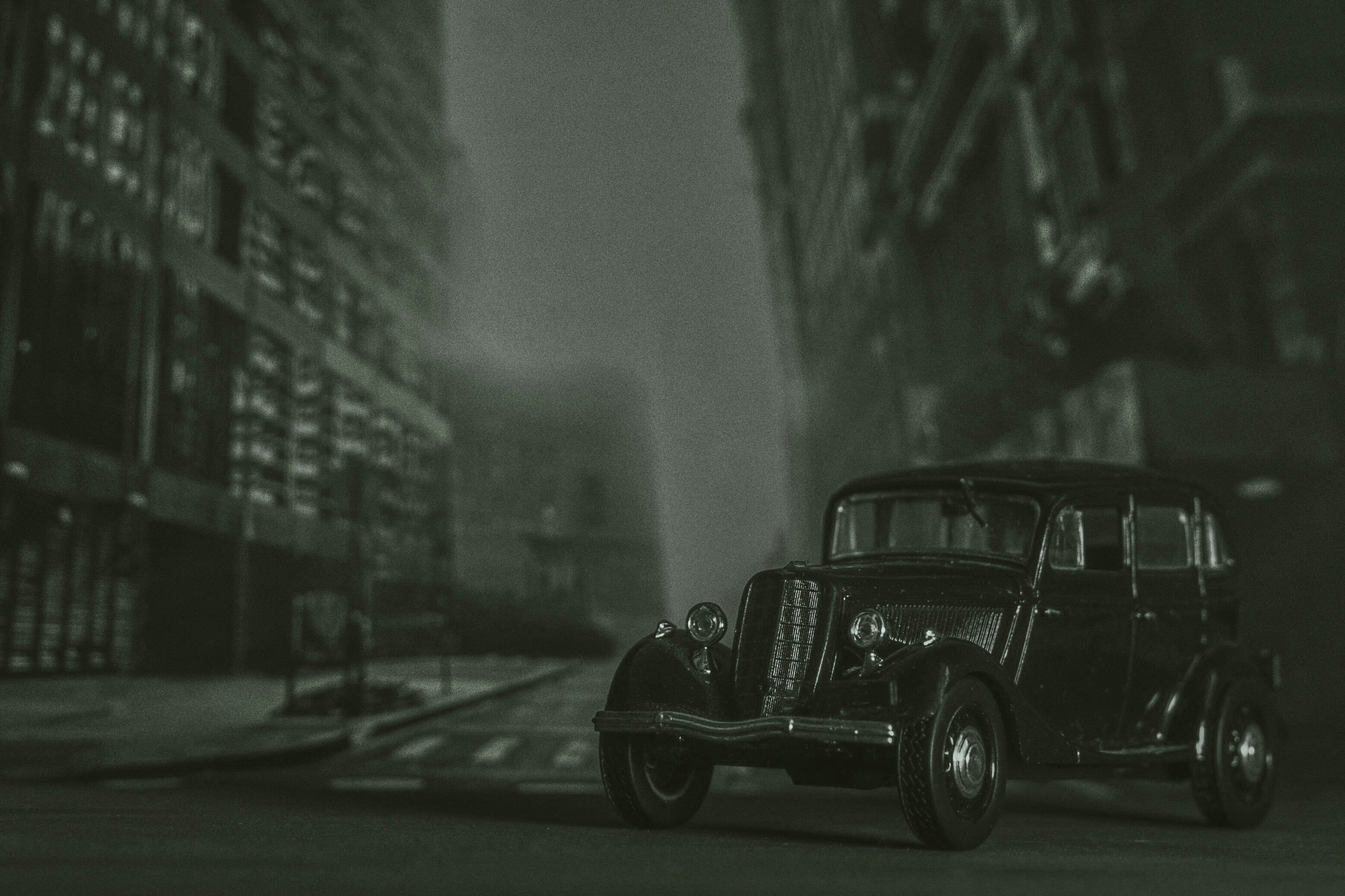 a black and white photo of an old car on a city street