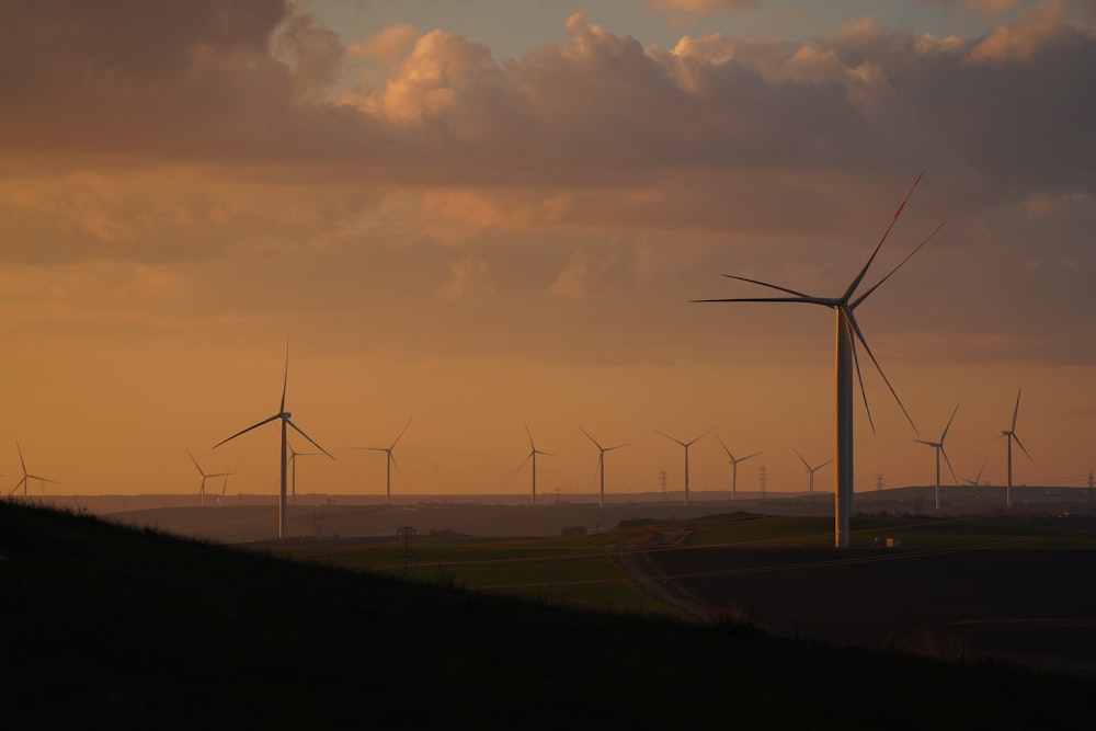a group of windmills on a hill with a sunset in the background