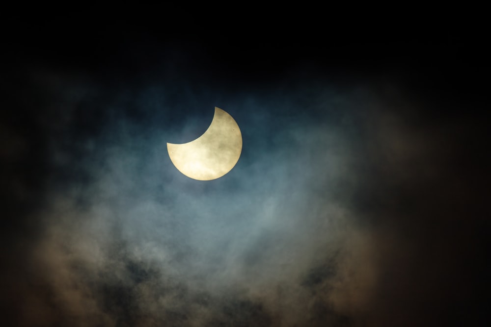 the moon is seen through the clouds during a partial solar eclipse