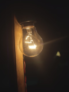 A bright light bulb glowing above a wooden table.