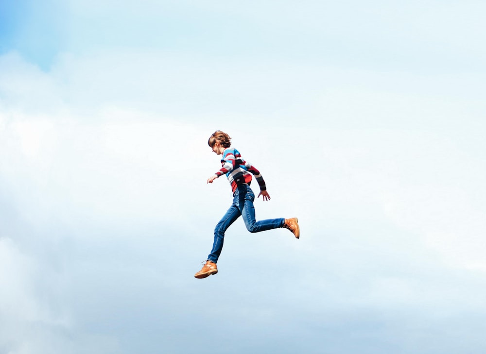 a woman flying through the air while holding onto a kite