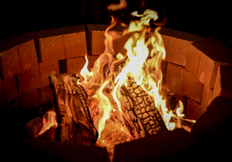 A wooden fire pit cooking grate glowing warmly over a crackling fire.