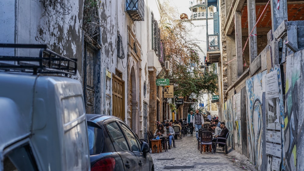 a narrow street with people sitting at tables