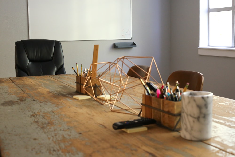 a wooden table topped with a cup filled with pens and pencils