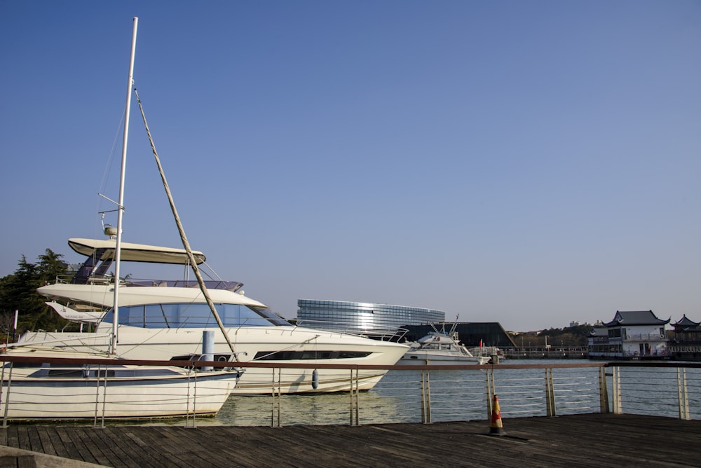 a white boat is docked at a pier