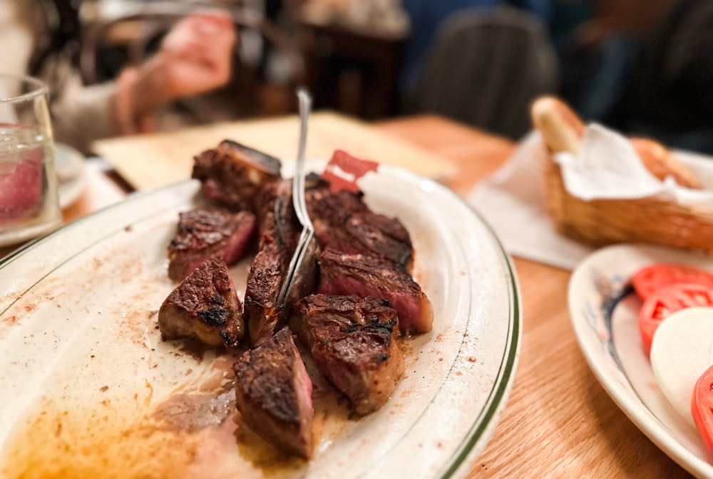 a plate of steak with a fork stuck in it