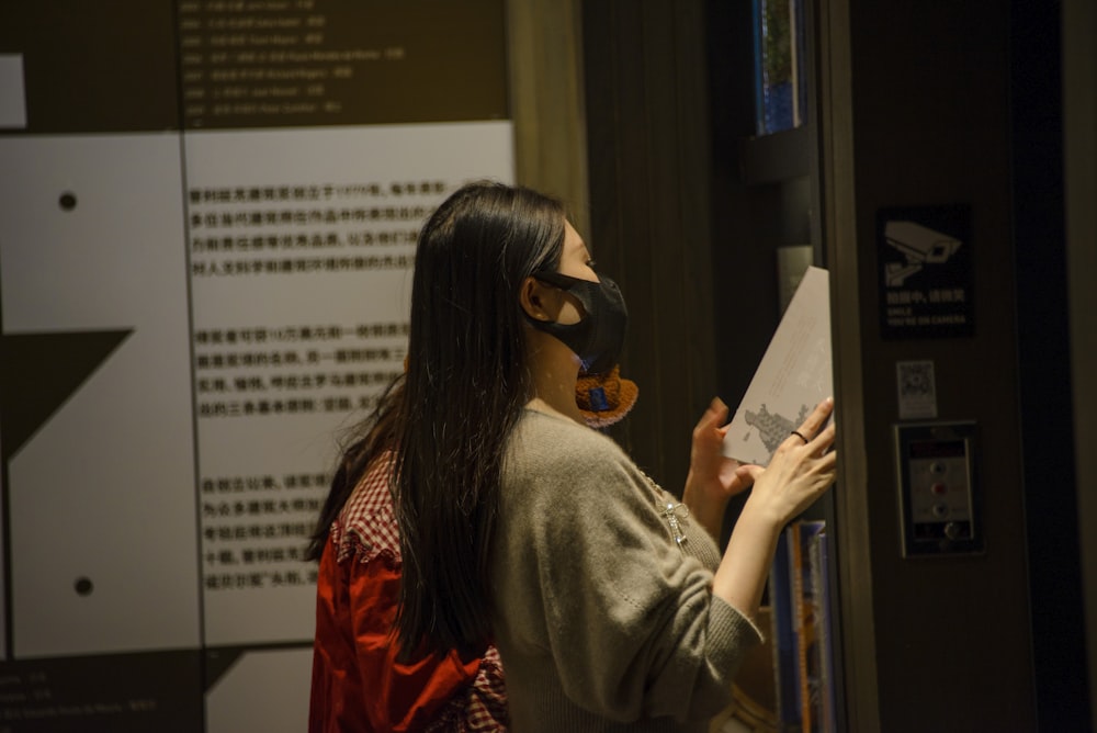 a woman wearing a mask looking at a piece of paper
