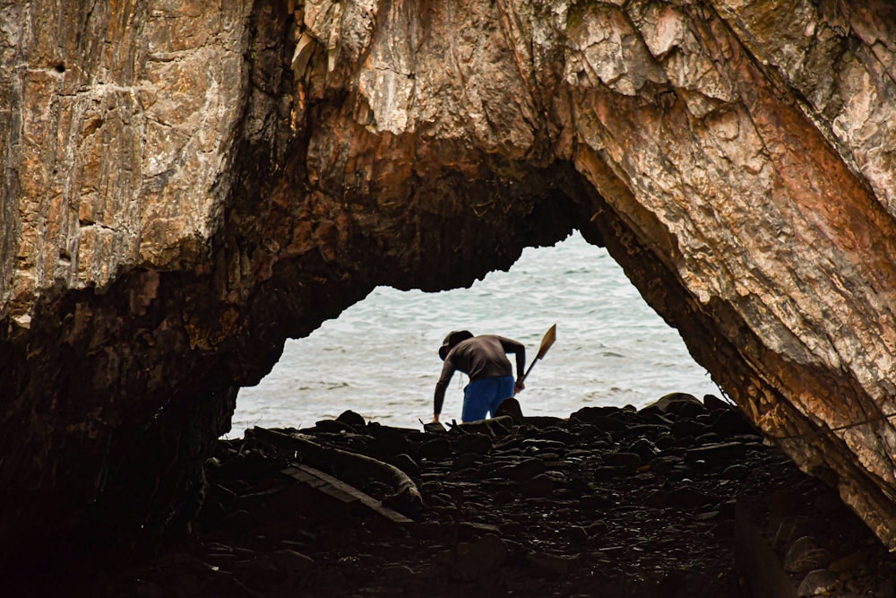 a man standing in a cave near the ocean