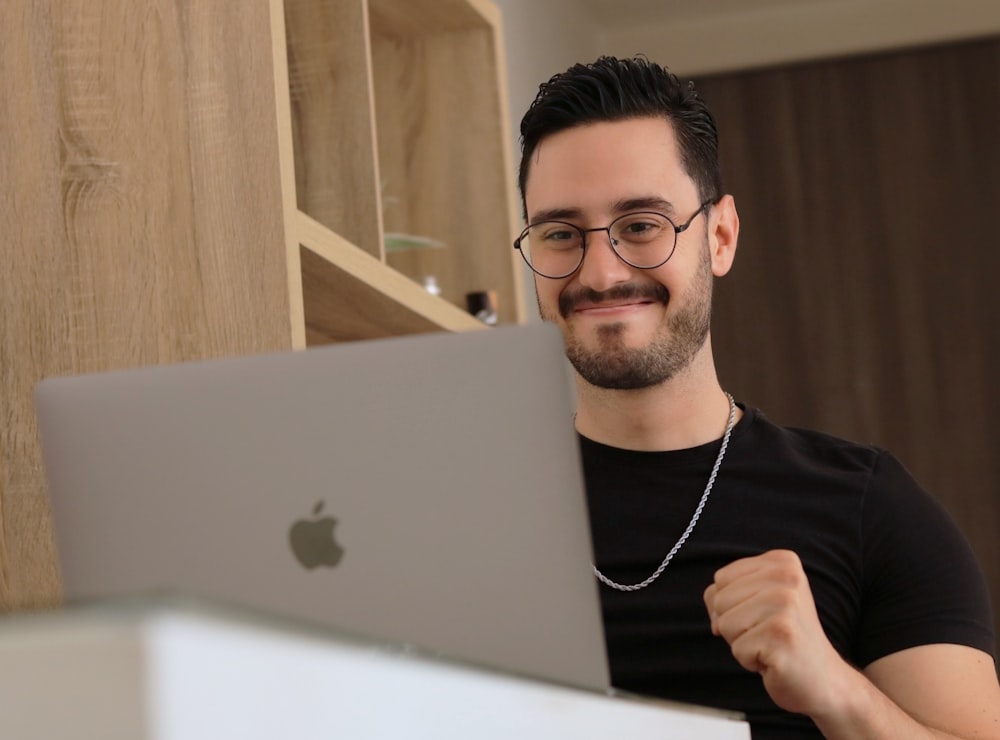 a man wearing glasses is looking at a laptop