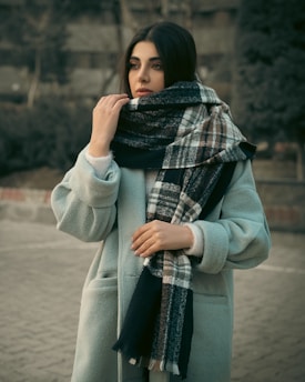 a woman wearing a blue coat and a plaid scarf