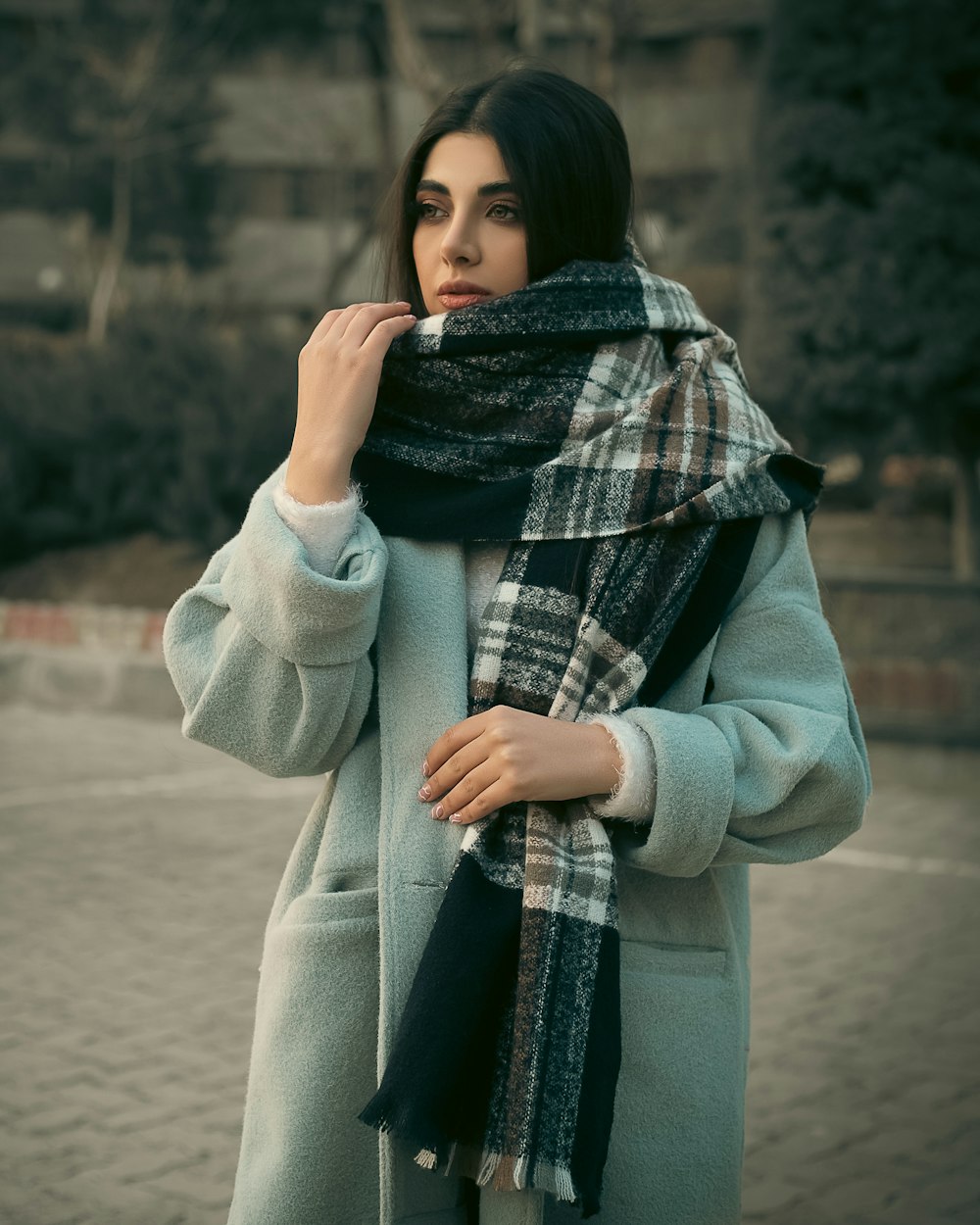 a woman wearing a blue coat and a plaid scarf
