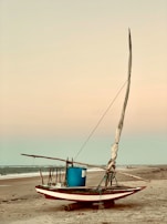 A traditional Mexican fishing boat resting on the shore at dawn.