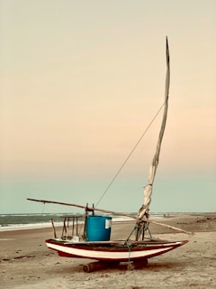 A traditional Mexican fishing boat resting on the shore at dawn.