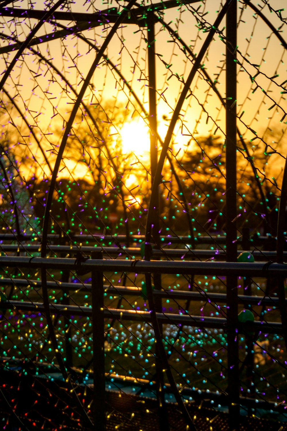 the sun is setting behind a wire fence