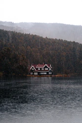 a house sitting on top of a lake next to a forest