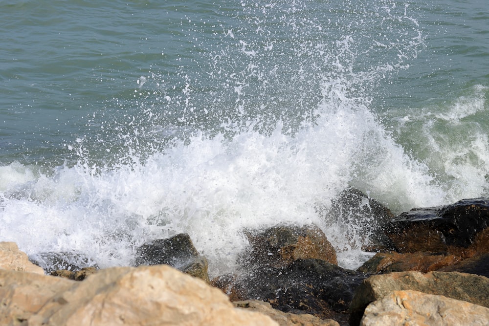 uma onda cai em rochas perto do oceano