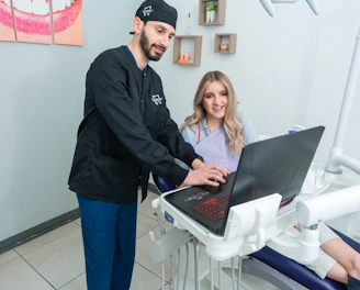 A friendly dentist gently examining a patient's teeth in a bright, peppermint-colored office.