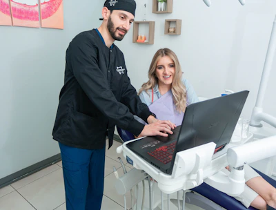 A friendly dentist gently examining a patient's teeth in a bright, peppermint-colored office.