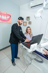 Smiling dentist gently treating a patient with modern dental equipment.