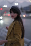 A model wearing a sleek solid color beret paired with a cozy scarf on a city street.