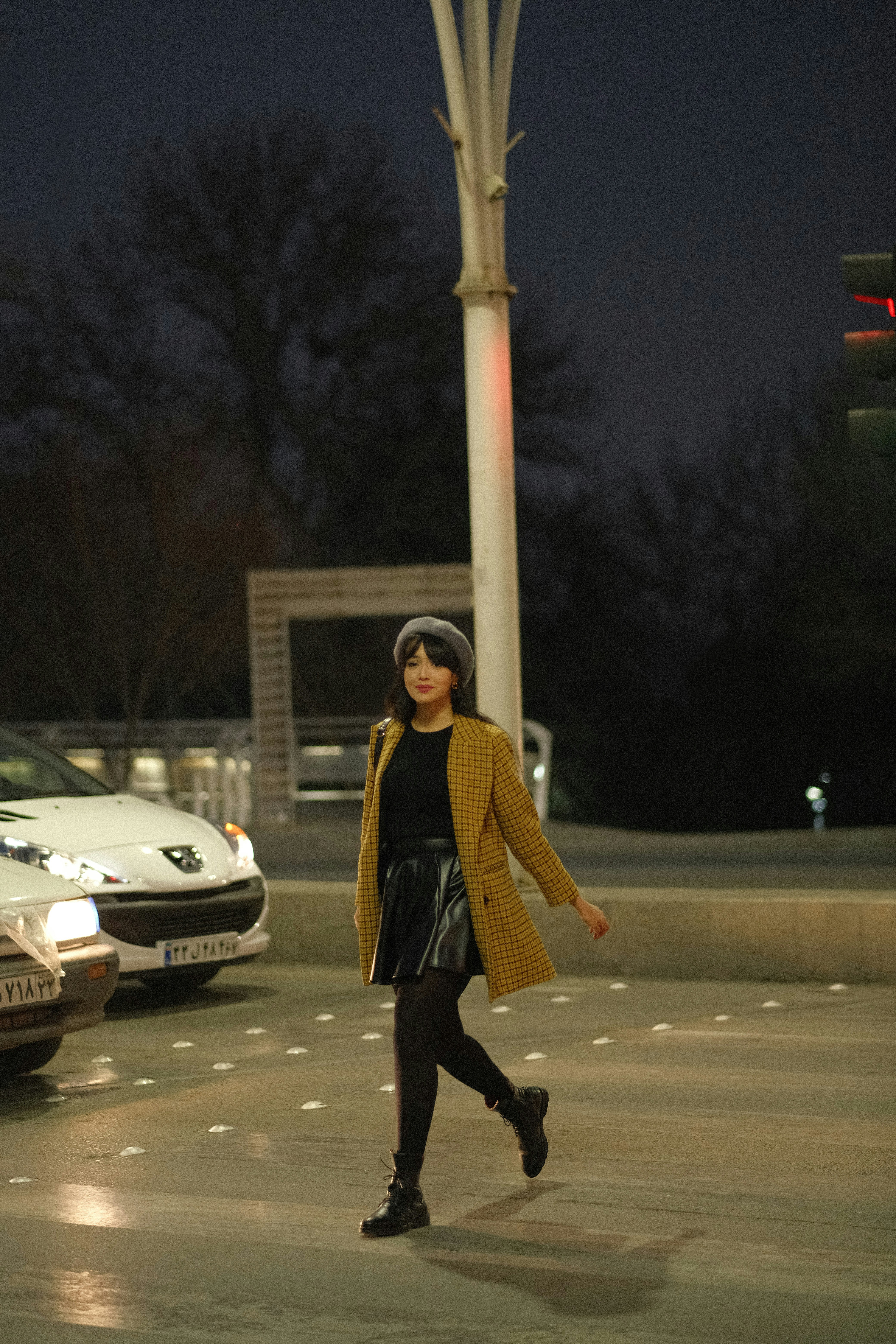 a woman walking across a street at night