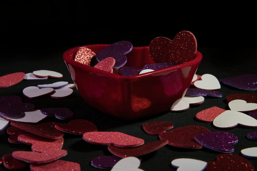 a red bowl filled with hearts on top of a table