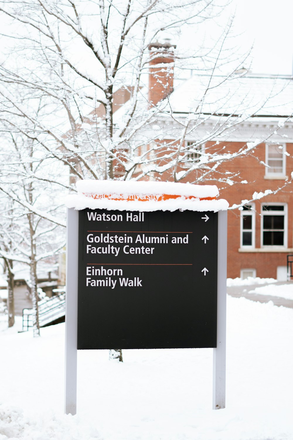 a sign that is in the snow near a building