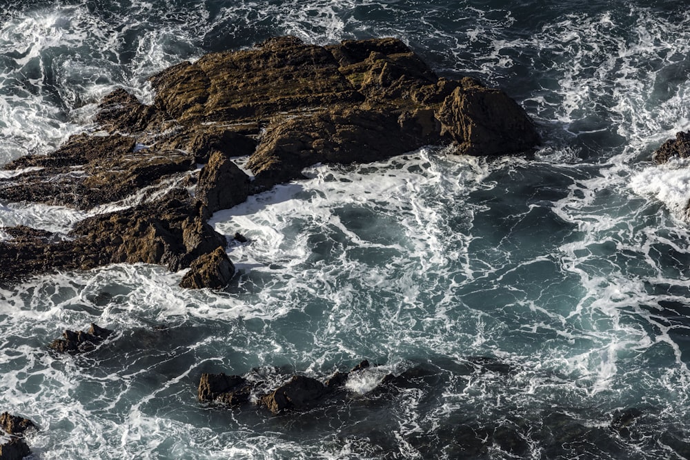 an aerial view of the ocean and rocks