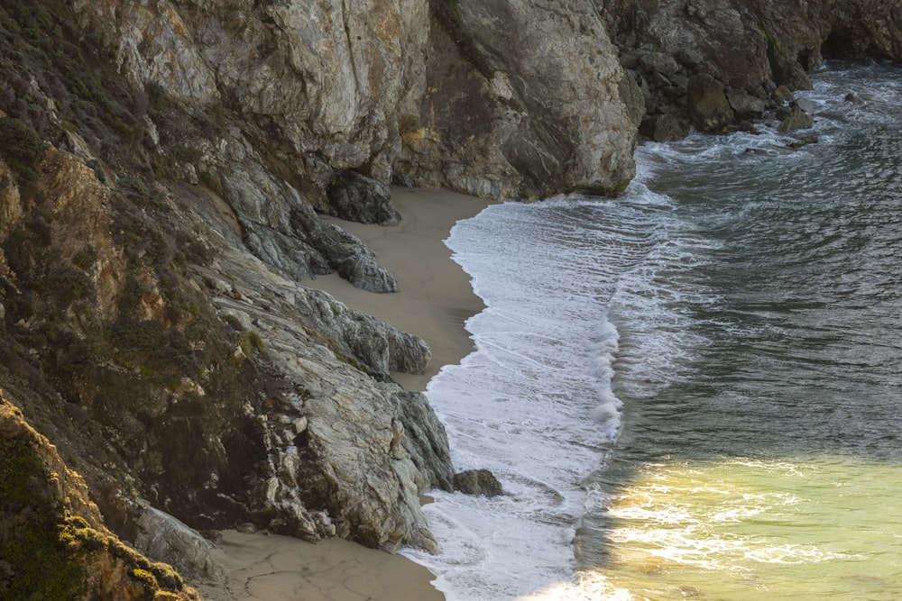 a sandy beach next to a rocky cliff